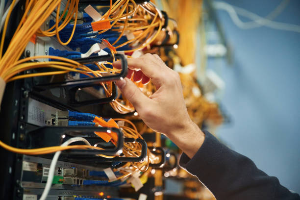 istock Young man is working with internet equipment and wires in server room 2030116239