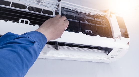 The concept of carrying out maintenance on the room air conditioning, a service technician cleaning the filter on the indoor air conditioning section,Maintenance process on the room air conditioning.