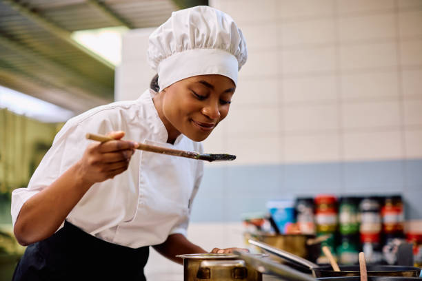 istock Happy black female chef tasting food while cooking in the kitchen. 2030122227