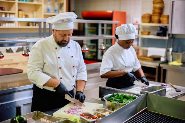 istock Mature chef and his black female assistant cooking in the kitchen. 2030122749