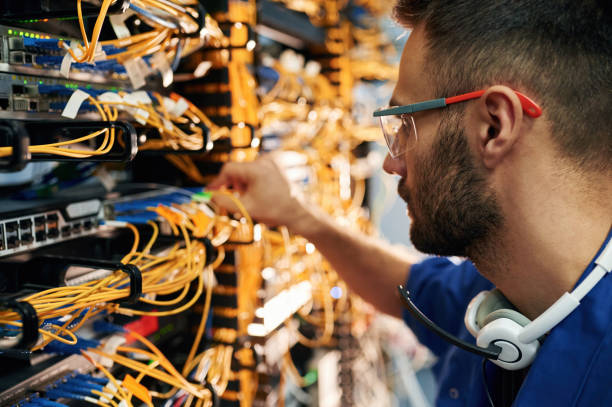 istock Modern technology routing. Young man is working with internet equipment and wires in server room 2030125390