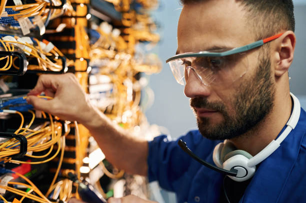 istock Modern technology routing. Young man is working with internet equipment and wires in server room 2030125392