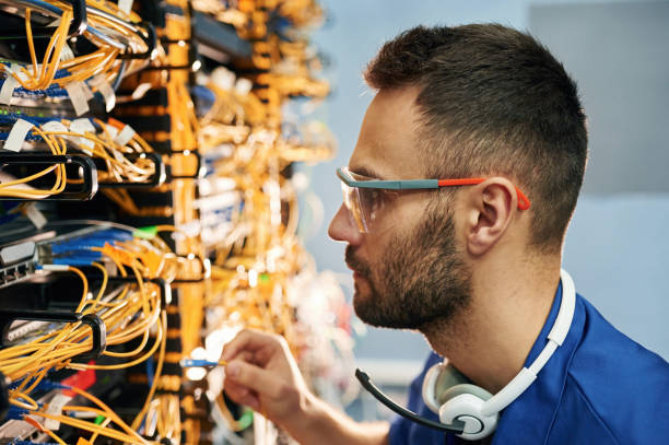 istock Modern technology routing. Young man is working with internet equipment and wires in server room 2030125394