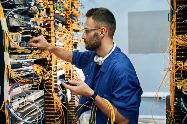 istock Modern technology routing. Young man is working with internet equipment and wires in server room 2030125917