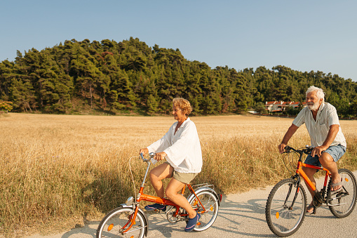 Photo of a senior couple, enjoy their time together while riding bicycles on a hot summer afternoon