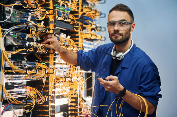 istock Looking to the camera. Young man is working with internet equipment and wires in server room 2030127493