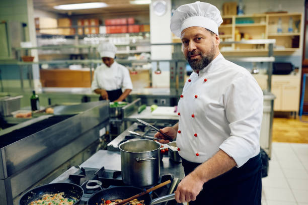 istock Mature cook preparing a dish while working in the kitchen and looking at camera. 2030128044