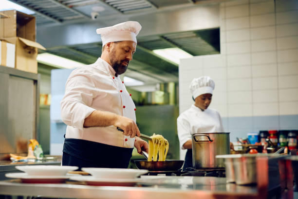 istock Male chef cooking pasta in the kitchen in a restaurant. 2030129102