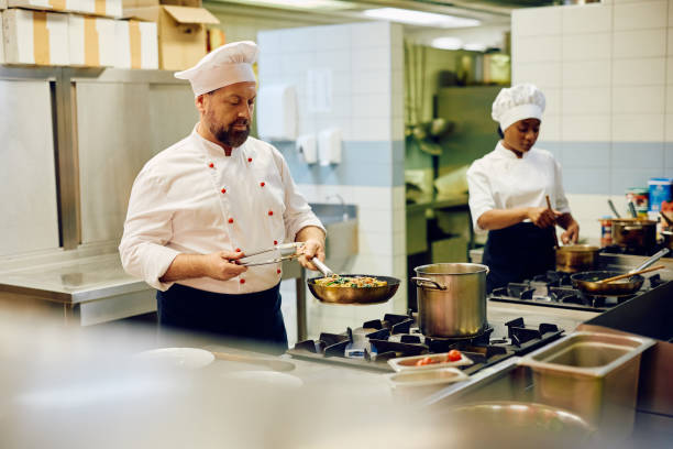 istock Mature chef cooking while preparing a meal in the kitchen in a restaurant. 2030129105