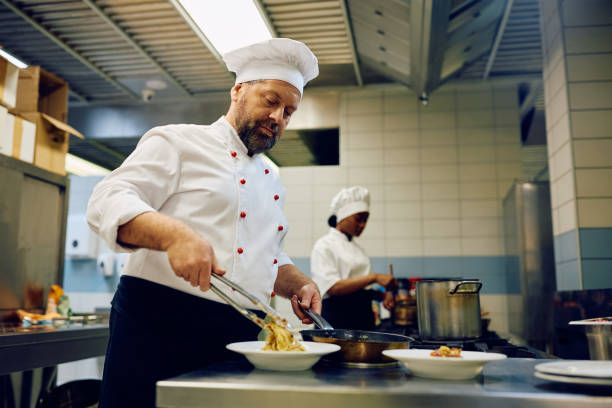 istock Mature cook serving a dish in a restaurant kitchen. 2030129114