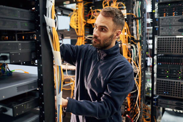 istock Black clothes. Young man is working with internet equipment and wires in server room 2030129636