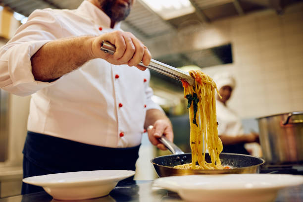 istock Close up of chef serving pasta while cooking in the kitchen. 2030130150