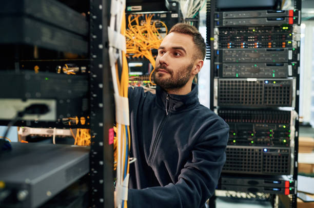 istock Black clothes. Young man is working with internet equipment and wires in server room 2030130162
