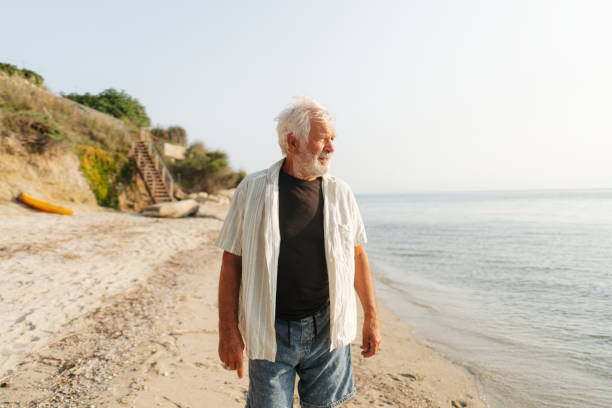 istock Senior man taking a walk down the beach 2030130739