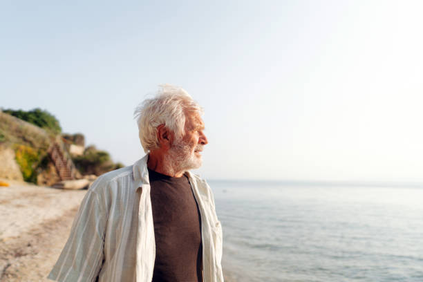 istock Senior man taking a walk down the beach 2030130741