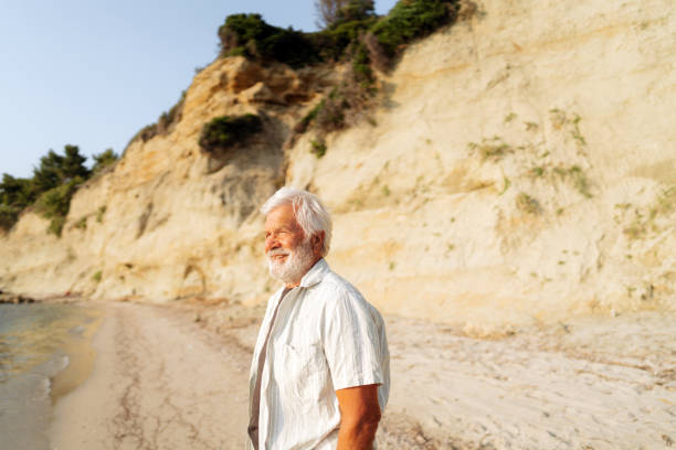 istock Senior man taking a walk down the beach 2030131531