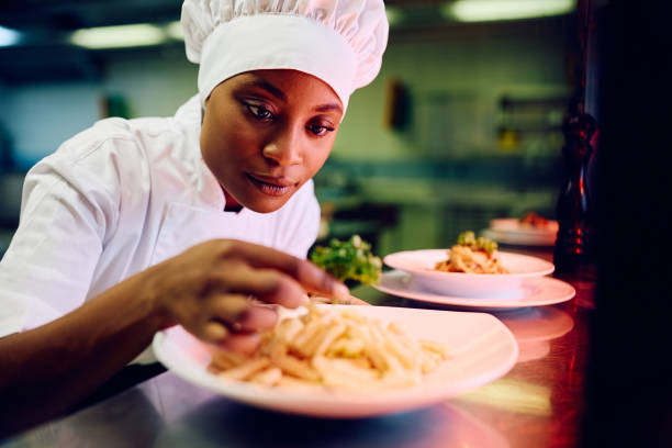 istock Black female cook decorating a dish while serving food in a restaurant. 2030132372