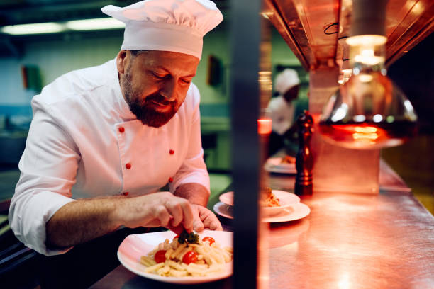 istock Smiling chef decorating food plate while serving meal in a restaurant. 2030133948