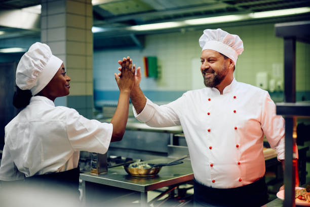 istock Happy professional chefs giving high-five while working in restaurant kitchen. 2030134866