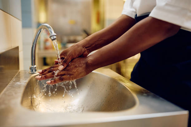 Close up of professional chef washing her hands while working in the kitchen.