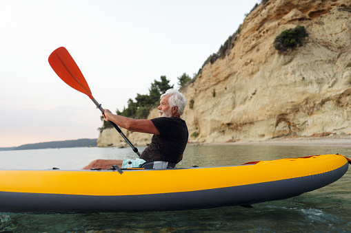 Photo of a senior man kayaking on a calm sea water