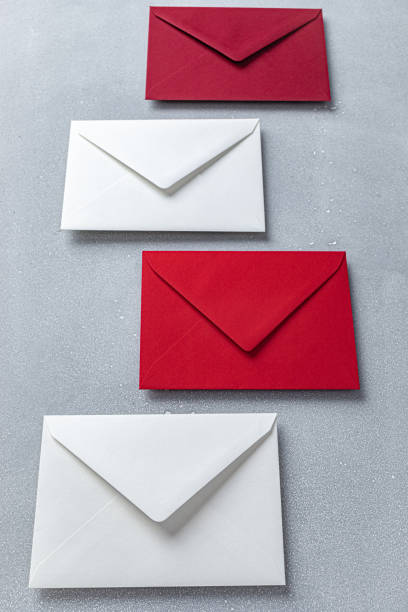 istock Assortment of Red and White Envelopes Arranged on a Grey Surface 2030158207