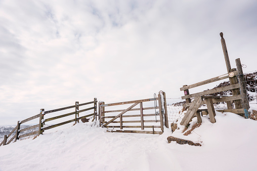 Timber gate and step-over platform forming entrance to Hole of Horcum, a natural depression and attraction, following snow storm near Goathland, Yorkshire, UK.