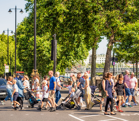A side view of people crossing at a busy intersection in Westminster, on a sunny August day in central London.