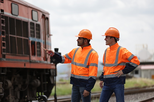 Portrait of two smart railway engineers with locomotive at yard train, train freight transportation