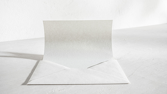 Blank White Paper In Envelope on Desk With Soft Shadows in Office.