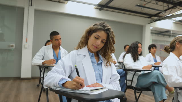 Group of Latin American medical students sitting in the classroom listening to a lecture and taking notes