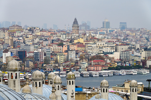Istanbul, Turkey - December 12, 2023: View on Golden Horn and Istanbul sityscape  from courtyard of Suleiman or Suleymaniye Mosque through the domes at winter evening
