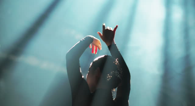 Silhouette of Ballerina performing hands flow movements in spotlights.