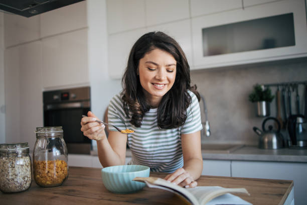 istock beautiful adult woman reading a book while having breakfast. 2030238636