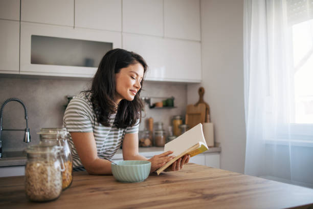 istock beautiful adult woman reading a book while having breakfast. 2030240208