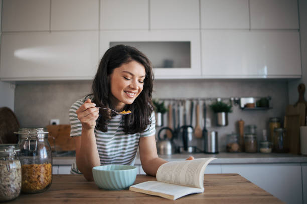 istock beautiful adult woman reading a book while having breakfast. 2030243411