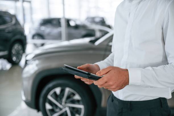 istock Black colored tablet in hands. Worker in formal clothes is in the auto salon 2030243422