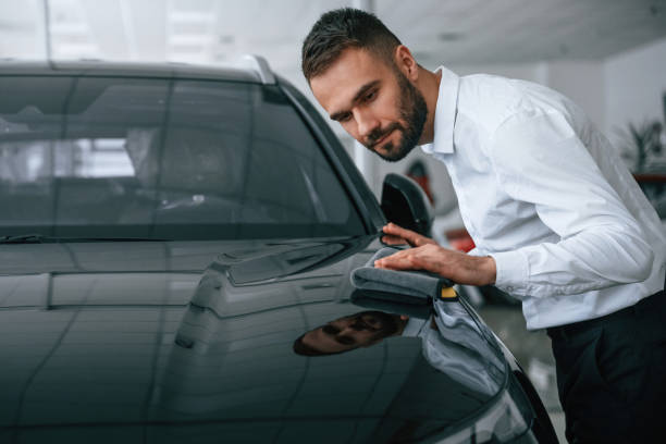 istock Looking at polished surface. Worker in formal clothes is in the auto salon 2030245523