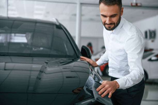 istock Looking at polished surface. Worker in formal clothes is in the auto salon 2030246057