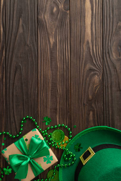 istock Whimsical St. Patrick's display from vertical top view, including shamrocks, pixie's hat, lucky coins, boxed surprises, bead garlands, and confetti, on a green canvas, with a spot for message 2030247764