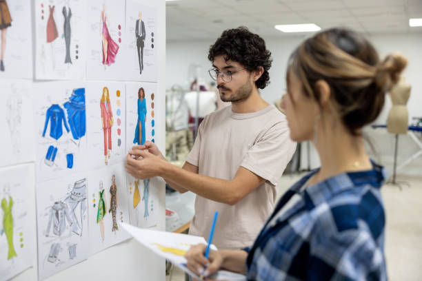Fashion design student explaining his designs to his teacher