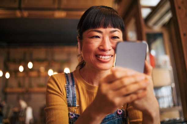 istock Yapanese woman using mobile phone and enjoying coffee at cafe 2030274789