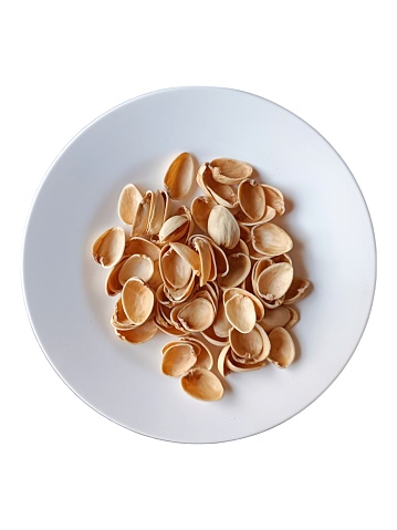 A plate of pistachio shells, the aftermath of a delicious snack. The shells are scattered around the plate, some of them still holding onto their precious nuts.