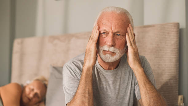 istock Senior man sitting on bed looking worried 2030297772