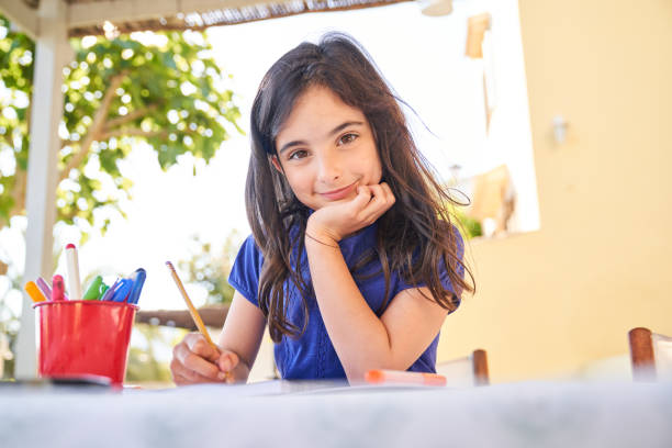 istock Charming girl sitting at table and drawing picture 2030310926