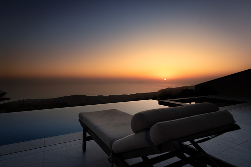 A chair elegantly placed on a patio overlooking a shimmering swimming pool, creating a tranquil and inviting atmosphere.