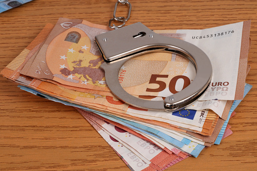 Financial crime concept with handcuffs on a wad of euro banknotes