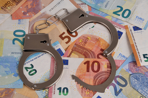 Financial crime concept with handcuffs on a background of euro banknotes