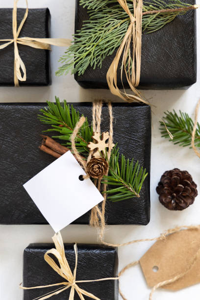 istock Black Christmas present with blank square gift tag, with fir branch and decorations, Mockup 2030325915