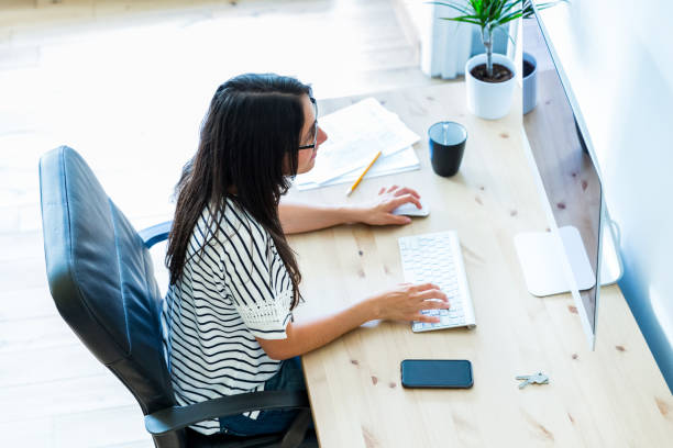 istock Productive young woman working on computer at home office 2030338441